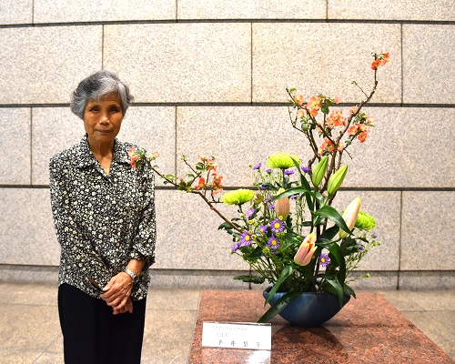 生け花の横に作者が立っている写真