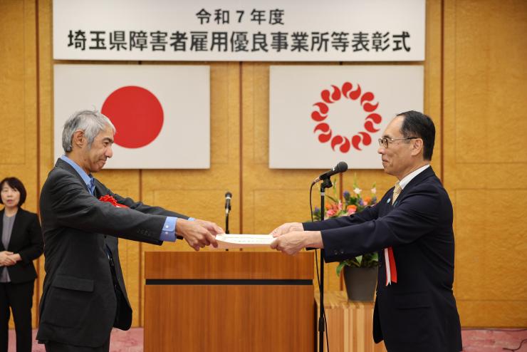 表彰式で受賞者に賞状を手渡す知事の写真