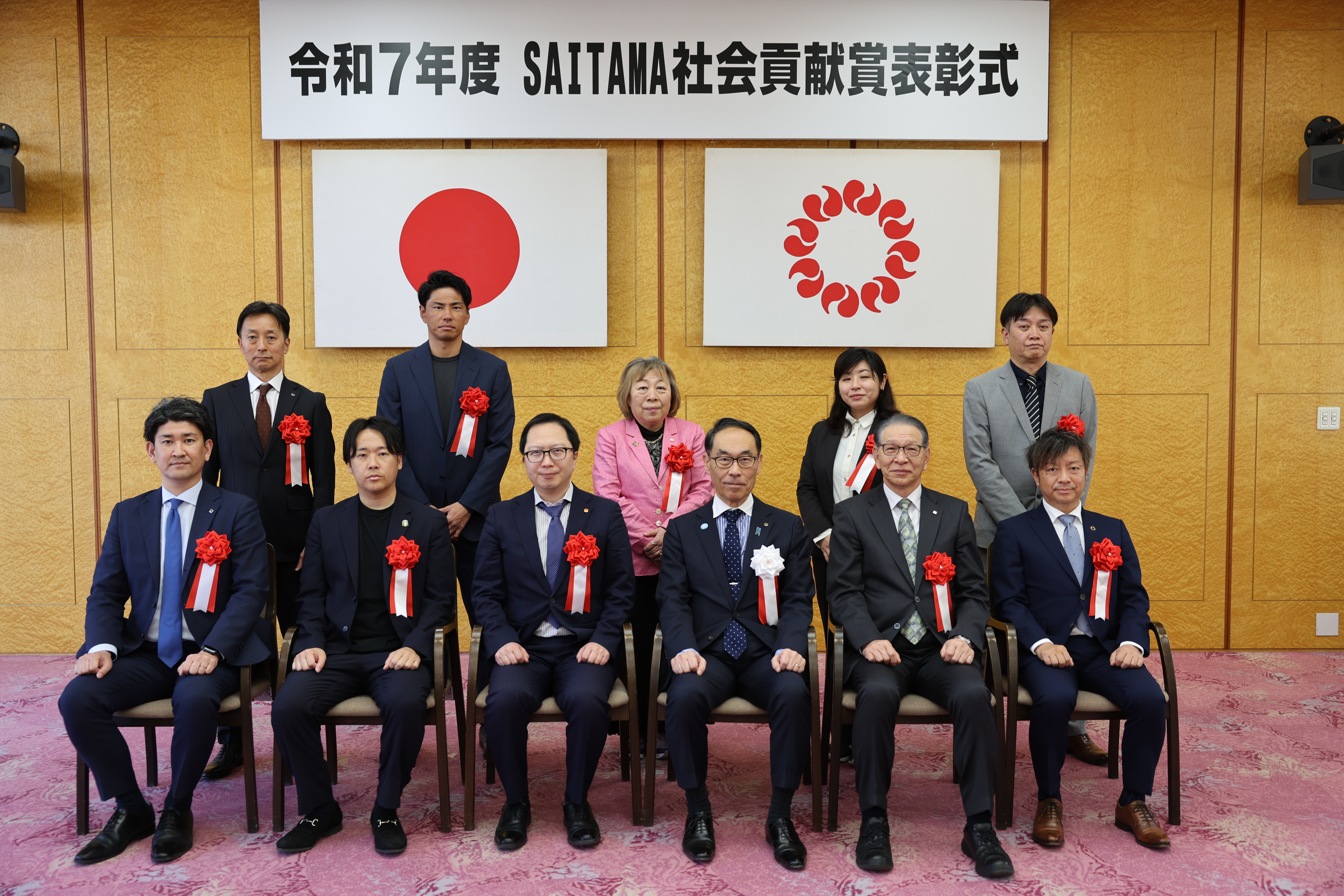 表彰者と集合写真に写る知事の写真