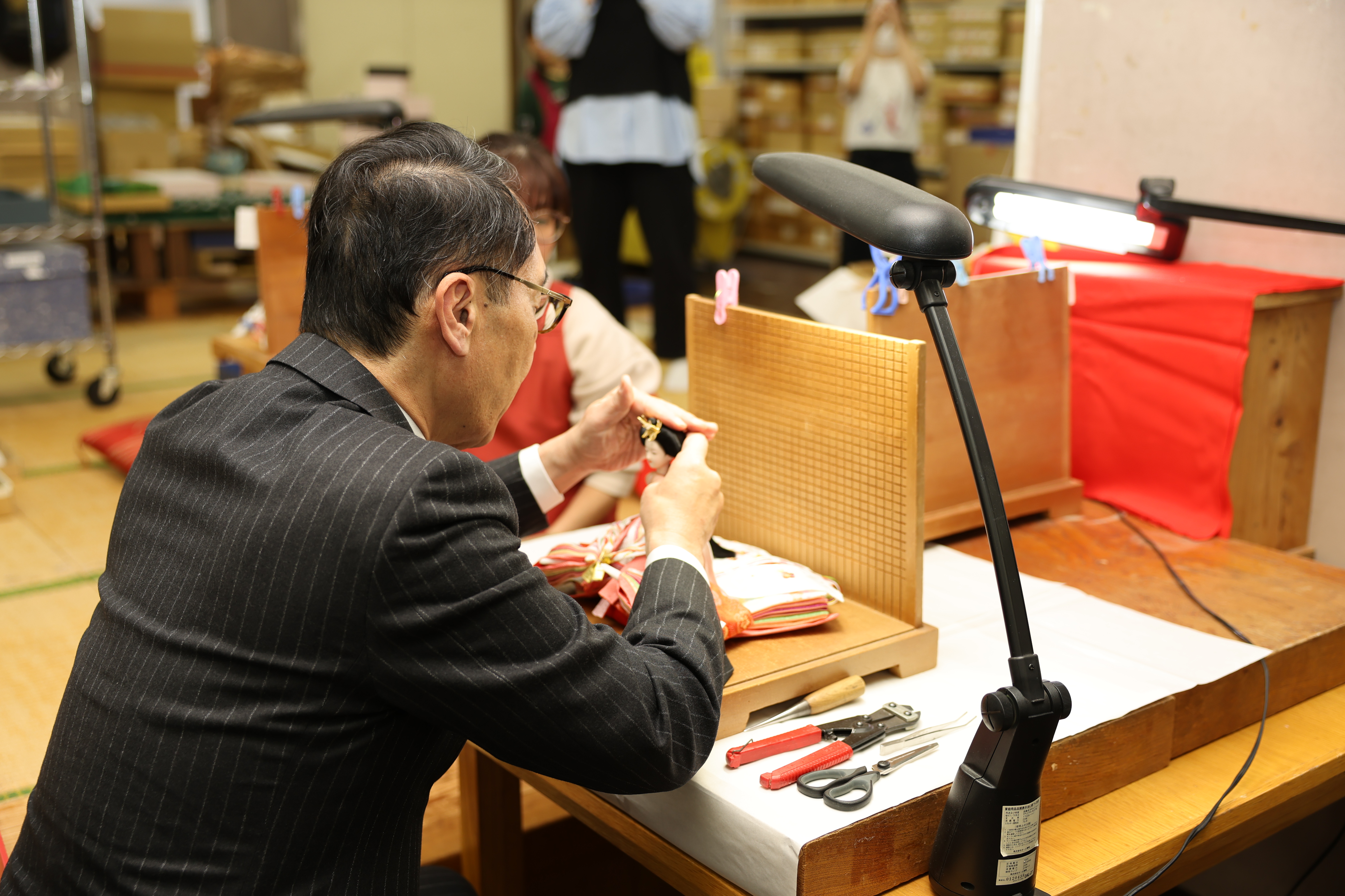 訪問先で人形を手に取る知事の写真