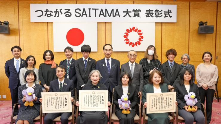表彰式で訪問者と集合写真を撮る知事の写真