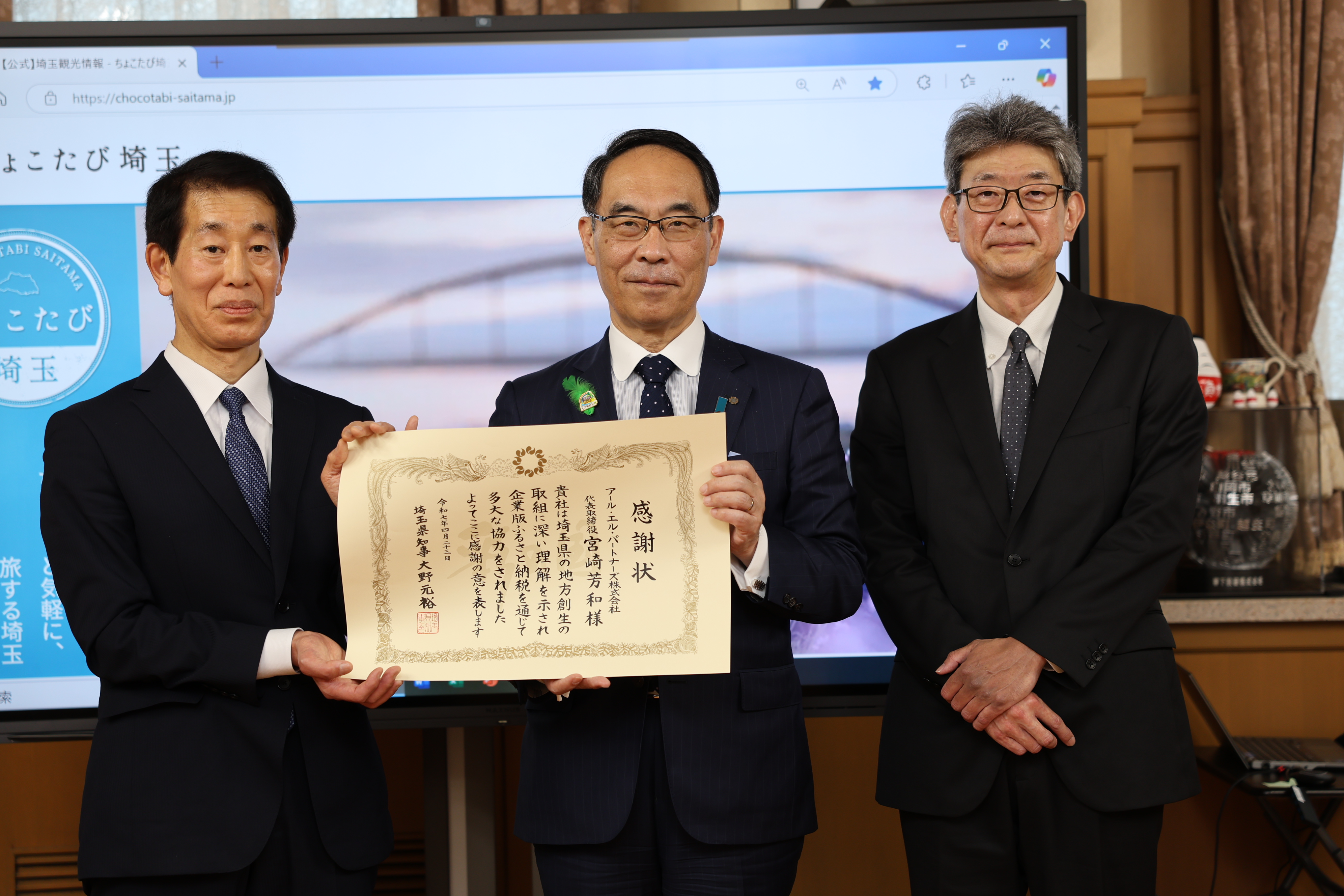 感謝状贈呈式で訪問者と記念写真を撮る知事の写真