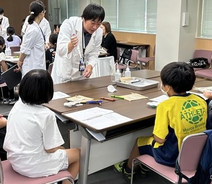 職員が参加者にマイクロピペットについて説明する様子の写真