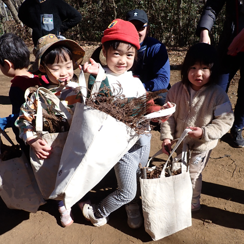 園内で集めた落ち葉を持つこどもたちの写真
