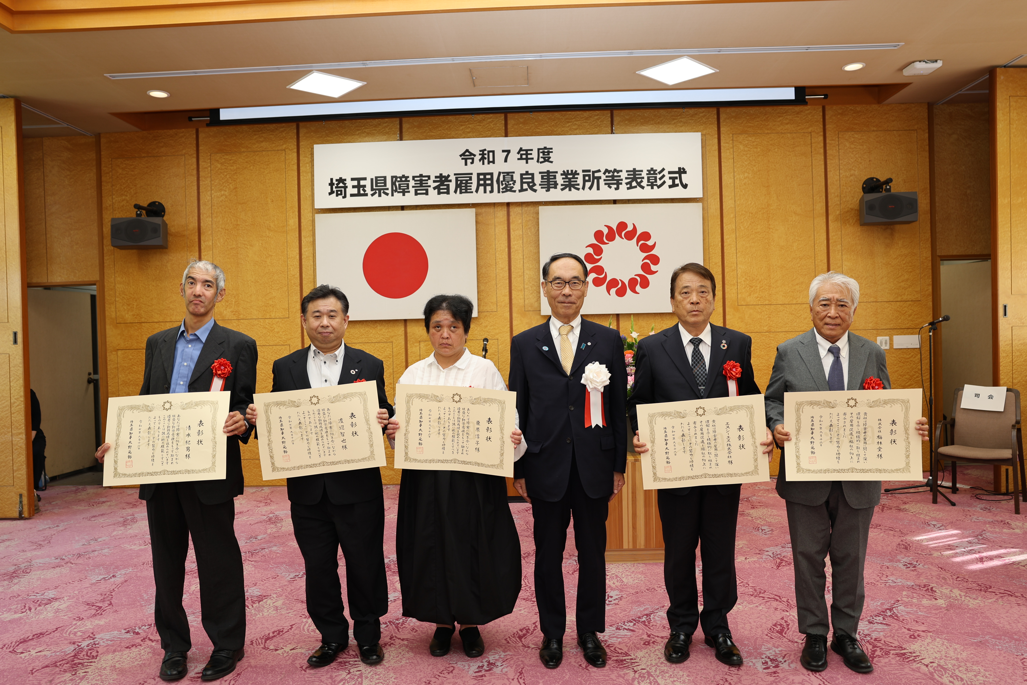 表彰式で受賞者と記念写真を撮る知事の写真