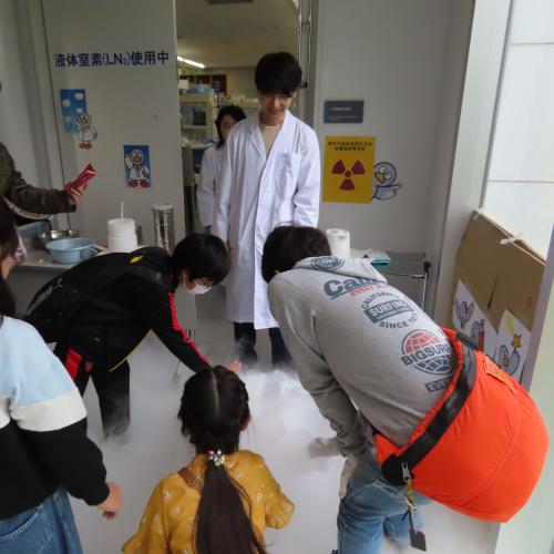 研究所公開の体験ブースで液体窒素の実験を眺めている来館者の写真