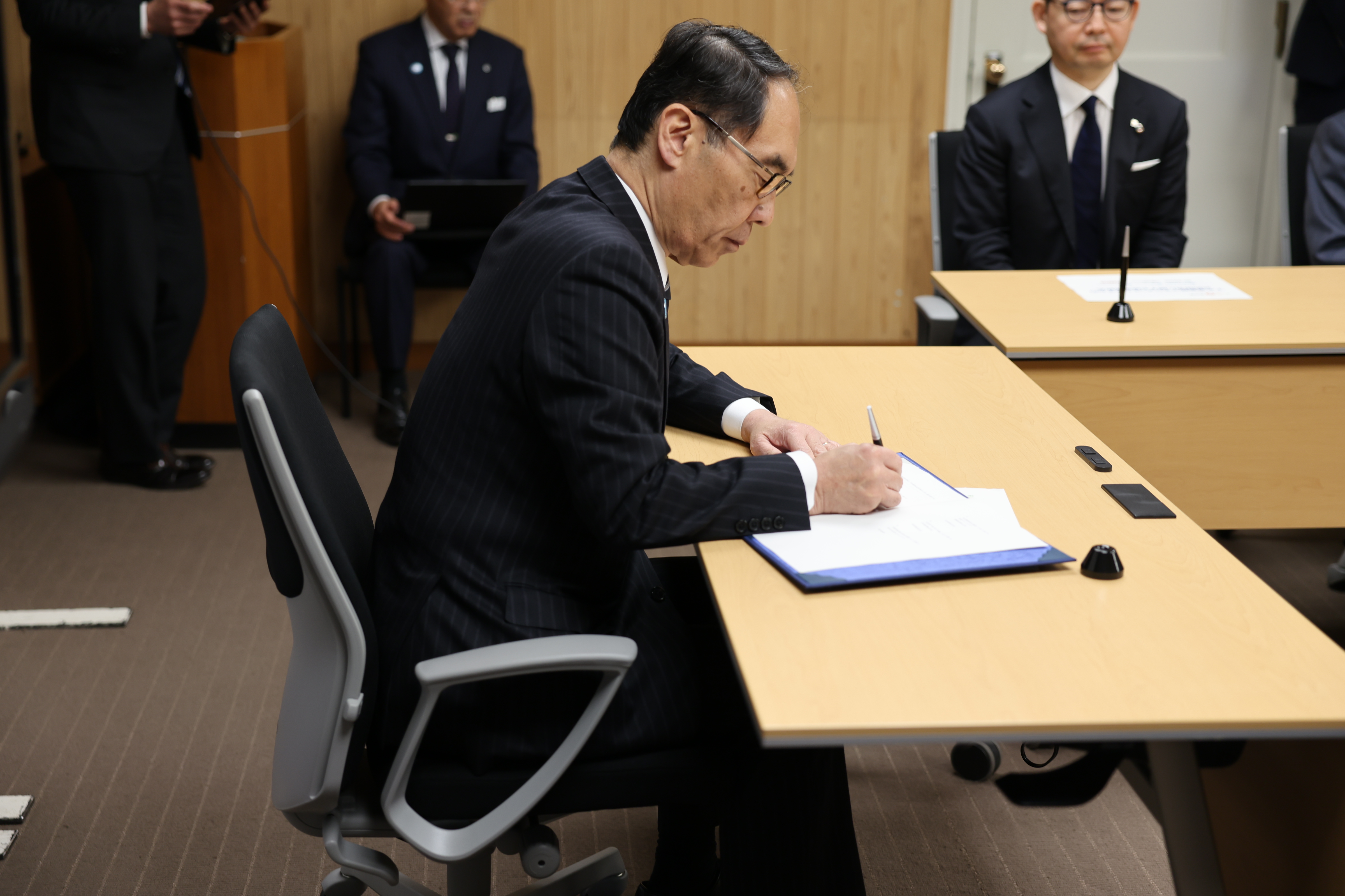 協定締結式でサインを書く知事の写真