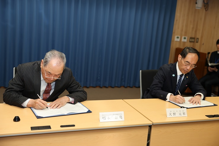 協定締結式でサインを書く知事の写真