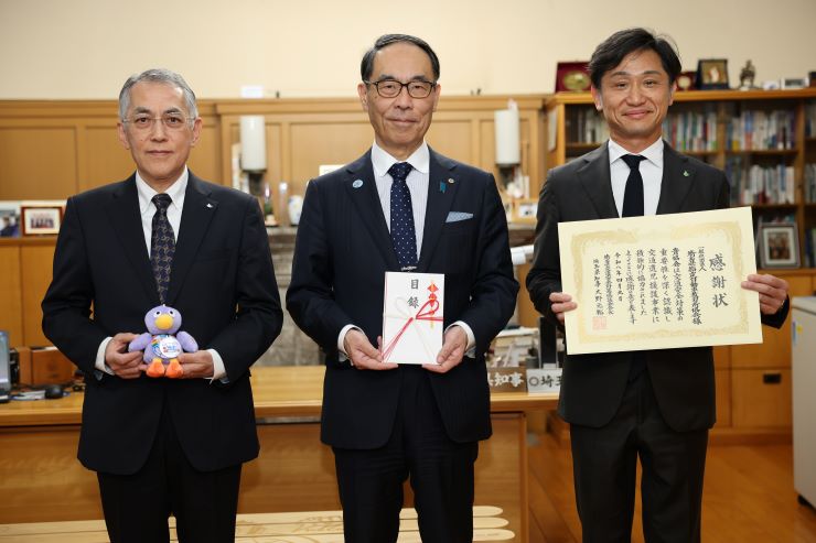 寄附いただいた方々と記念撮影を取る知事の写真