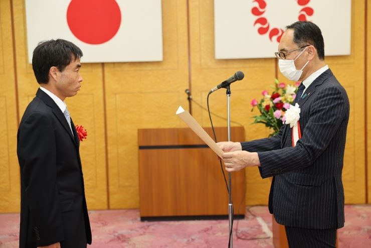 表彰式で賞状を受賞者に授与する知事の写真