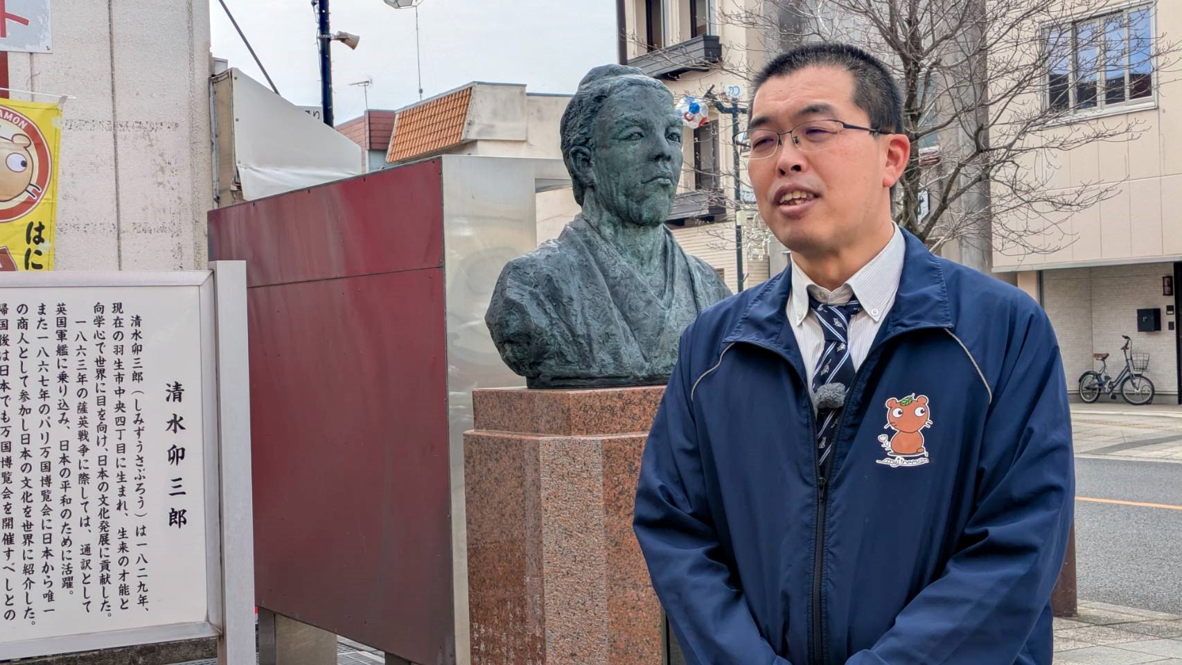 清水卯三郎の説明をする羽生市の職員